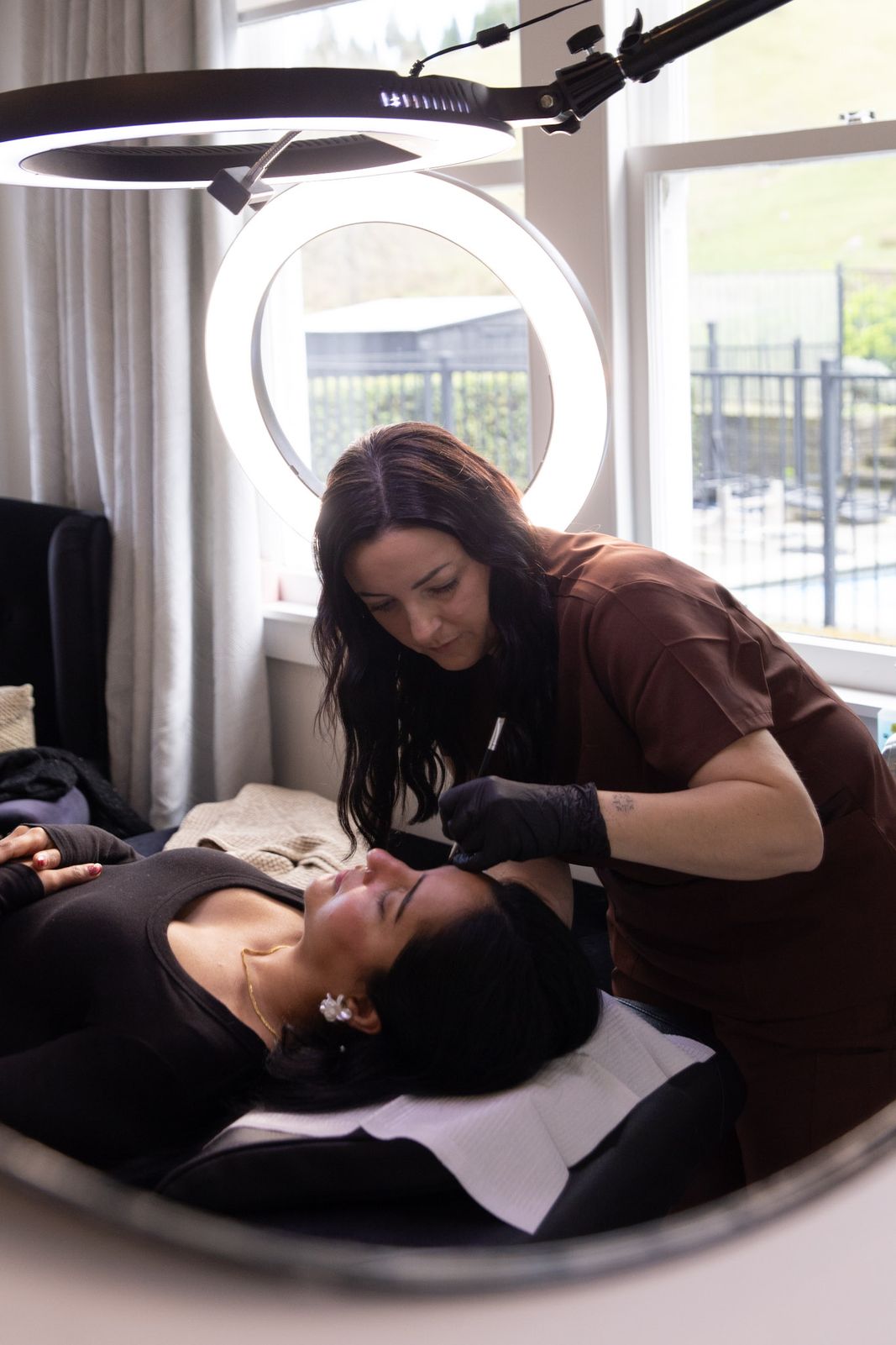 Vicki working on a client's brows under the ring light at The i-Brow Room studio in Napier