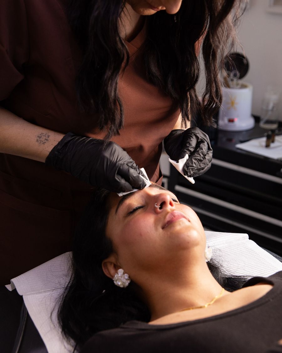 Vicki cleaning up a client's brows after treatment